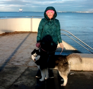 A young woman with a dog against the backdrop of the Baltic sea